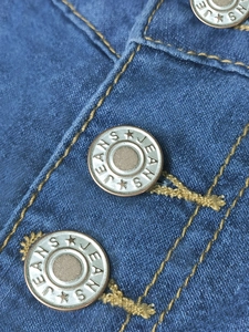 Close-up of deep blue denim skirt with vintage metal buttons and yellow stitching
