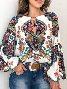 Détail d'une blouse bohème à imprimé floral avec glands et motifs de perroquets colorés