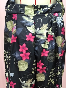 Detail of tropical floral print on black jumpsuit featuring pink flowers and green leaves