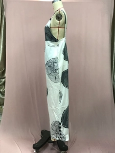 Detail view of artistic tree ring print and side button decor on white sleeveless jumpsuit