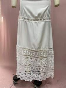 Close-up of bohemian white satin skirt with layered lace inserts and leaf patterns