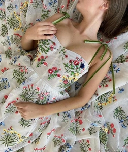 Detail der bunten Blumenstickerei auf weißem Netzkleid mit grünem Samtträgerband