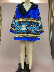 Détail d'un manteau bleu à capuche avec motifs tribaux et fermetures à brandebourg