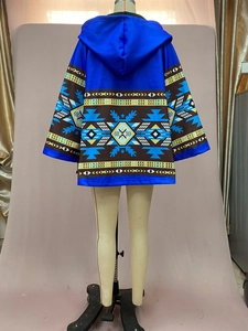 Détail du manteau bleu à capuche avec motifs tribaux sur le dos et les manches