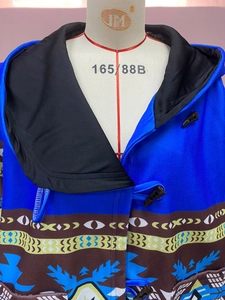 Détail d'un manteau à capuche bleu royal avec boutons en corne et motifs ethniques
