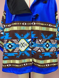 Détail du manteau à capuche bleu roi avec motifs ethniques et fermeture à boutons duffle-coat