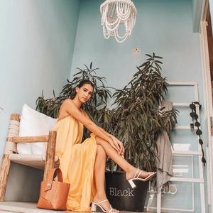 Detailed view of yellow maxi dress with ruffle hem and white block heel sandals