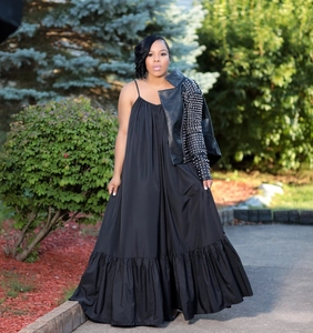 Close-up of black sleeveless summer dress featuring a wide ruffled hem with studded jacket