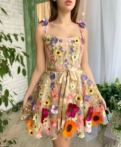 Détail de broderies florales 3D sur une robe en tulle beige avec ceinture en ruban