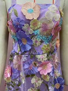 Détail de la broderie florale 3D colorée sur le tissu en tulle résille violet de la robe