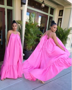 Bright pink halter maxi dress featuring a backless design and wide ruffled hem details