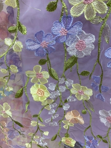 Vue macro détaillée de broderies florales 3D colorées sur tissu en maille lavande
