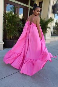 Detail of hot pink tiered maxi dress featuring thin straps and pleated voluminous skirt