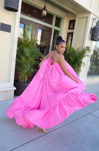 Detail of rose pink backless maxi dress with thin straps and ruffled hemline in sunlight