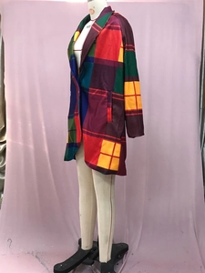 Detailed view of longline plaid coat featuring vibrant red, yellow, and blue color blocks
