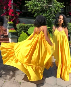 Detail of yellow backless summer maxi dress featuring spaghetti straps and ruffle tiers