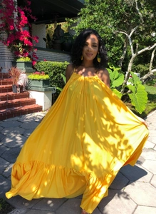 Detail of bright yellow summer maxi dress featuring spaghetti straps and ruffled hem design