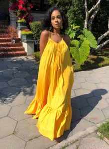 Detail of summer yellow maxi dress showing thin straps and ruffled hemline
