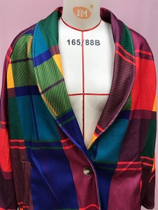 Detail of colorful plaid pattern coat with dark brown button on synthetic glossy fabric