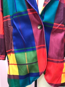 Detail of colorful plaid wool coat featuring notched lapels and single button closure