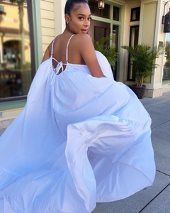 Detail of the multi-layered pleated hem of a white backless maxi dress in a sunny street