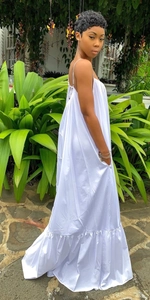 Detail of white backless maxi dress with thin straps and ruffled hem in tropical setting