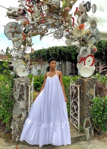 Detailed view of white sleeveless trapeze dress with ruffle hem in artistic outdoor setting