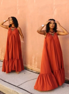 Detail of caramel orange halter neck maxi dress featuring tiered ruffle hem design
