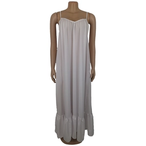 Detail of white summer dress showing thin straps, pleated neckline and ruffled hemline