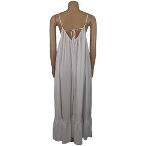 Detail of white maxi dress featuring backless tie-up design and ruffled hemline