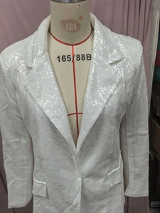 Detail of white sequined blazer with lapel collar and shimmering fabric texture on mannequin