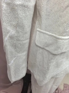 Detailed macro view of white sequined blazer fabric texture and pocket flap design