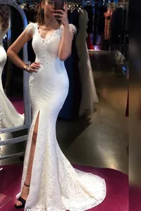 Dettaglio abito in pizzo bianco con spalle piumate ed elegante spacco alto laterale