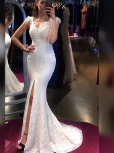 Abito da sera a sirena in pizzo bianco con scollo a V, piume e spacco alto sul davanti