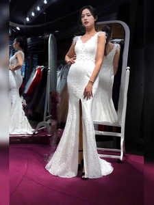 Elegante abito da sera in pizzo bianco con coda a sirena, piume e spacco frontale alto