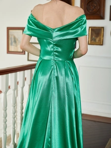 Détail de l'élégante robe de soirée en satin vert émeraude avec une encolure bardot