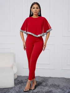 Combinaison rouge chic avec cape, détails en paillettes argentées et coupe ajustée