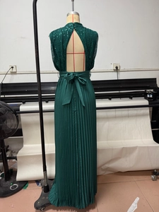 Detailed back view of emerald sequined maxi dress with halter open back and pleated skirt
