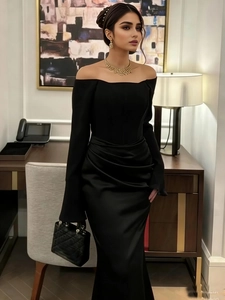 Detail of elegant black off-shoulder evening dress with waist pleats and gold jewelry