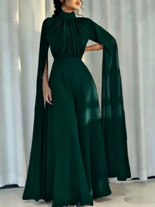 Dark emerald green high neck jumpsuit with pleated bodice and dramatic cape sleeves