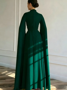 Deep green high neck jumpsuit featuring floor-length cape sleeves and elegant back view