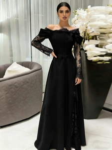 Close-up of black velvet evening gown featuring elegant lace sleeves and off-shoulder design