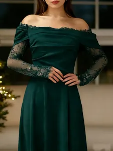 Détail de la robe en velours vert foncé à épaules dénudées et manches en dentelle fine