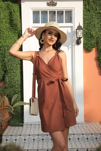 Close-up of caramel sleeveless wrap dress with V-neckline and waist tie detail