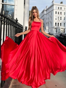 Macro shot of smooth red satin fabric and flowing hem on backless evening dress