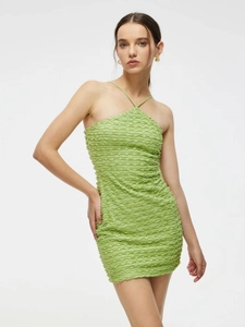 Detail of light green bodycon mini dress with ruched texture and halter neck design