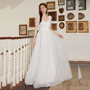 Detail of elegant white tulle bridal gown featuring floral lace appliques and puff sleeves
