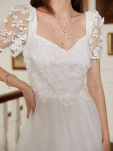 Detail of white French vintage lace dress featuring 3D floral embroidery and puff sleeves