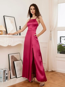 Detail van elegante magenta satijnen maxi-jurk met een hoge split en een halterhals