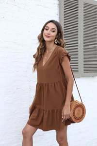 Detail of a dark brown V-neck tiered dress with ruffle sleeves and bohemian accessories